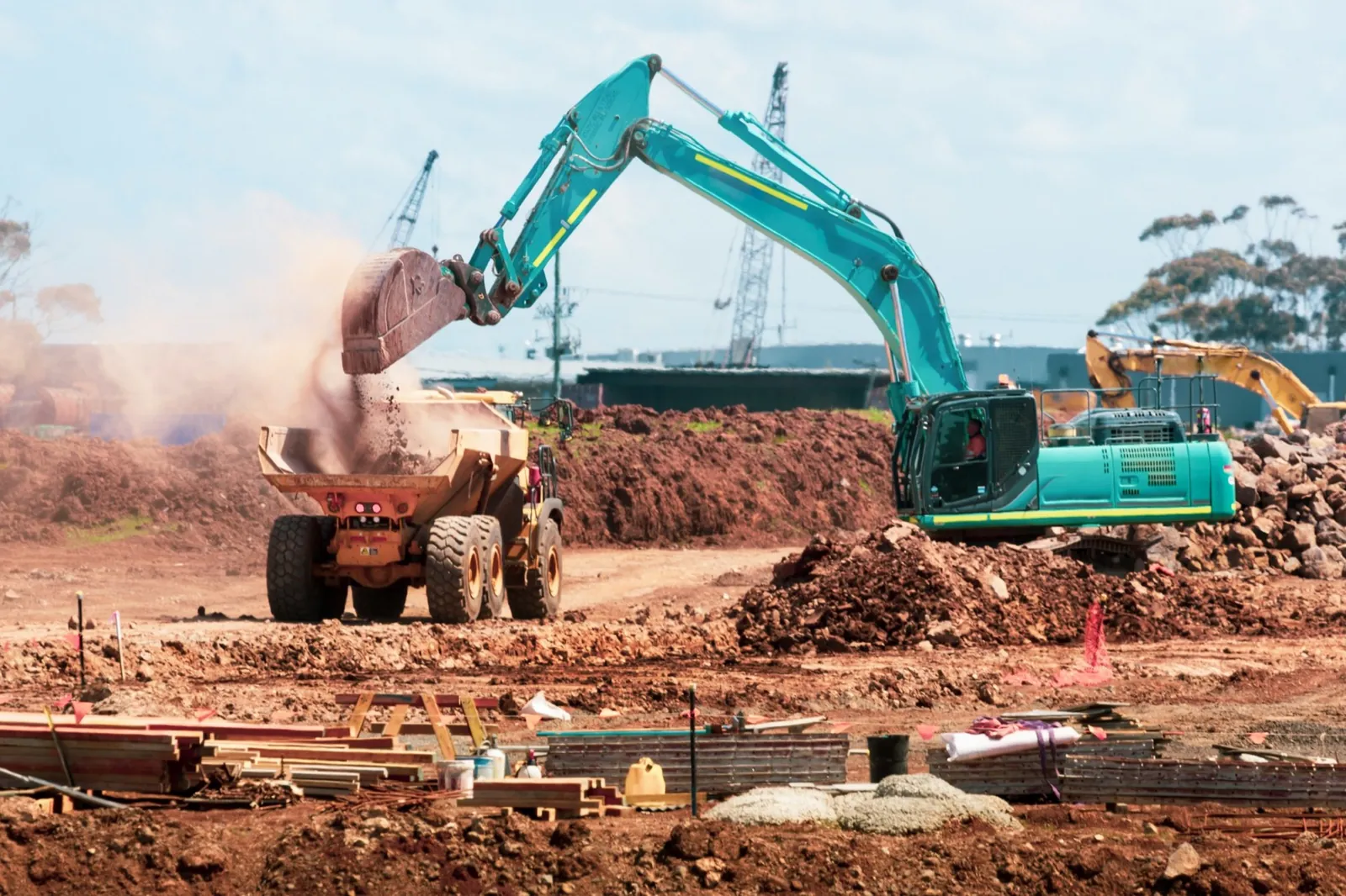 Excavator încărcând pământ într-o autobasculantă pe un șantier de infrastructură